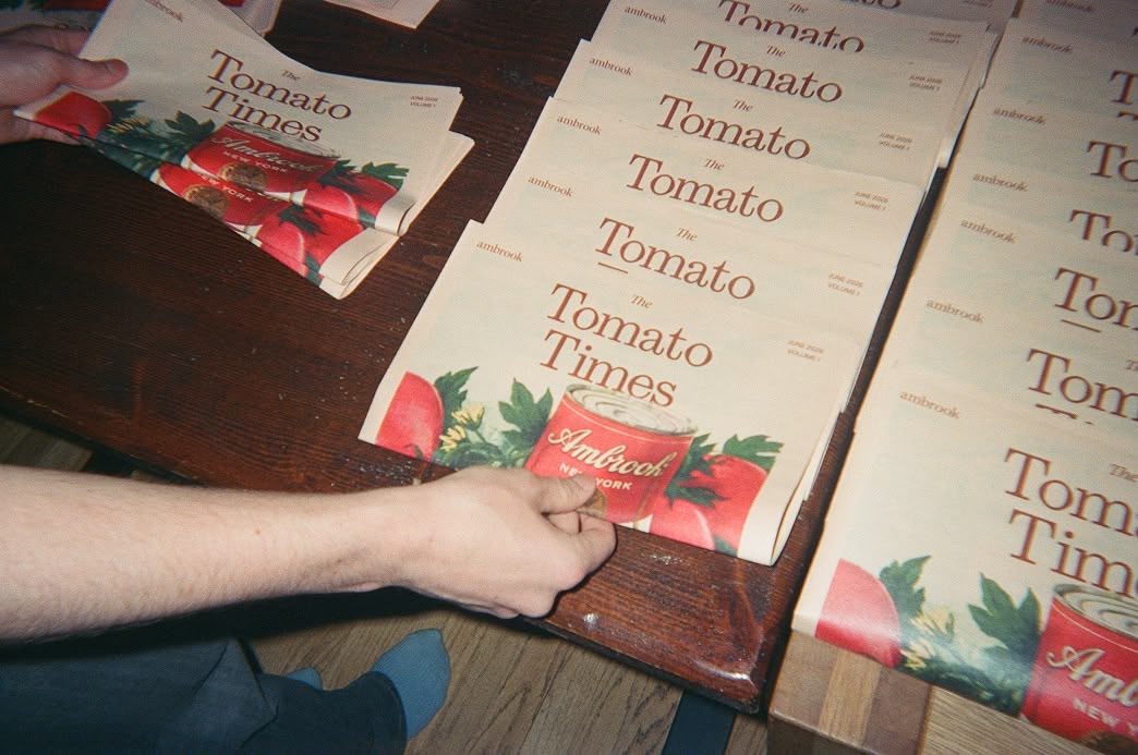 Stacked copies of The Tomato Times newspaper spread across a wooden table.
